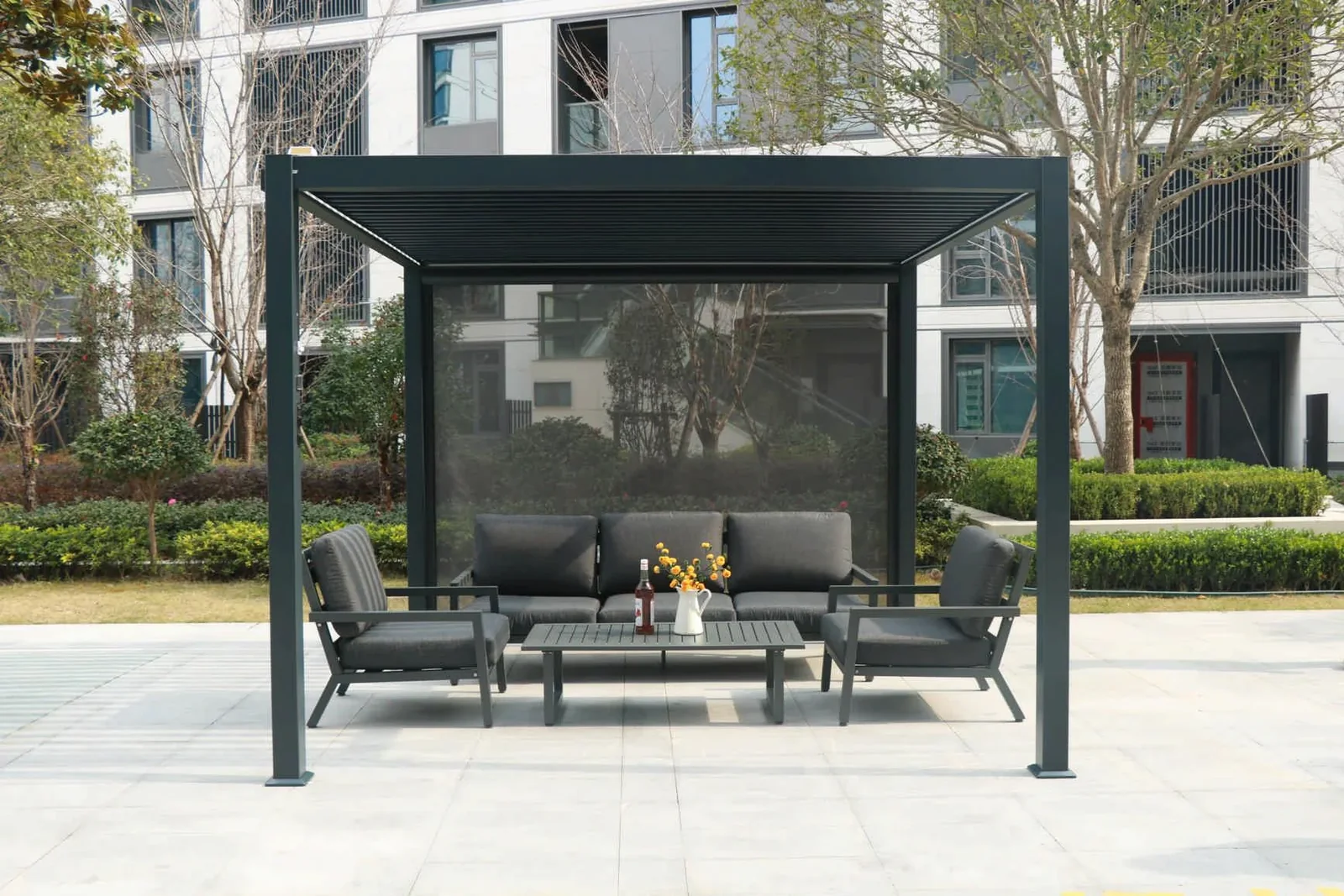 Freestanding dark grey louvered pergola with outdoor lounge furniture