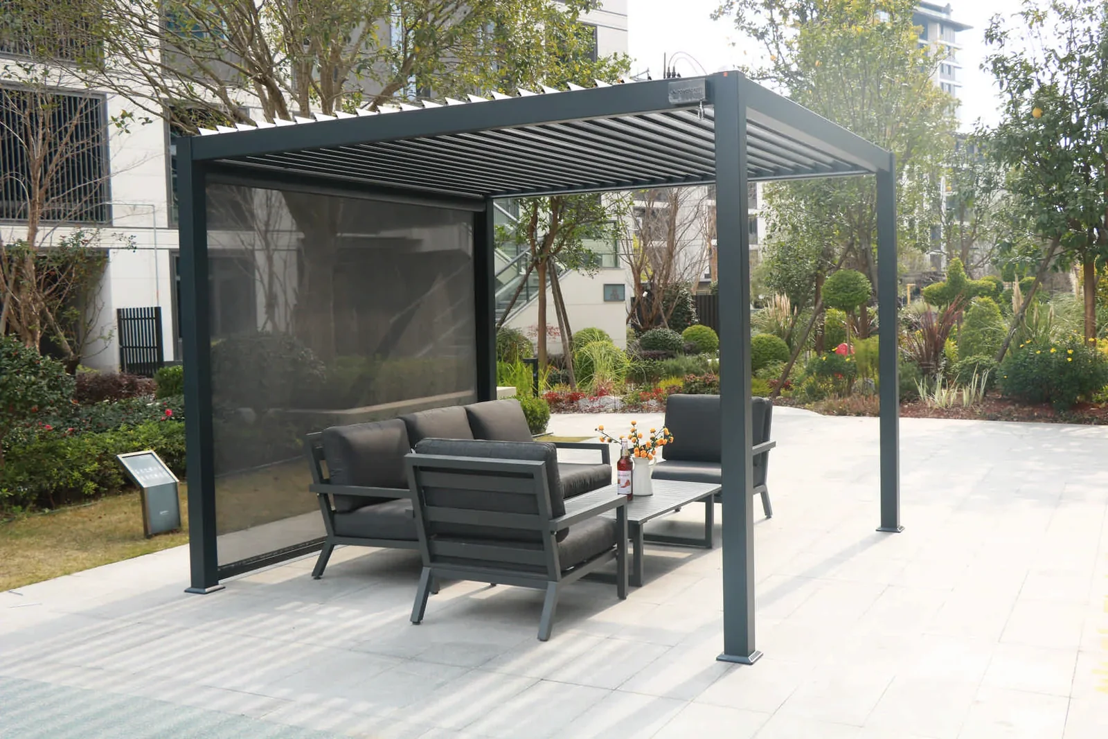 Louvered pergola with sofa seating in a landscaped outdoor setting